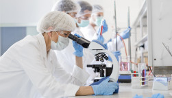 Scientists in protective suits in a science laboratory study a virus