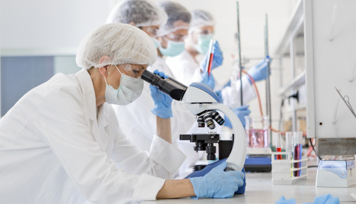 Scientists in protective suits in a science laboratory study a virus
