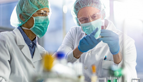 Two scientists cooperating while examining antiviral drug in a test tube at laboratory