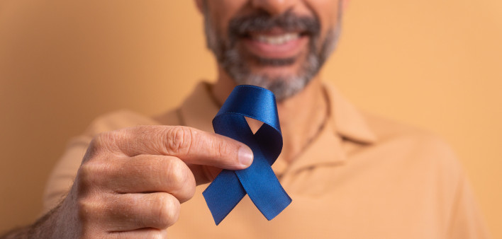 man holding blue ribbon for prostate cancer awareness