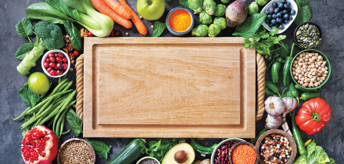 Healthy food selection with fruits, vegetables, seeds, super foods, cereals and the cutting board in the middle