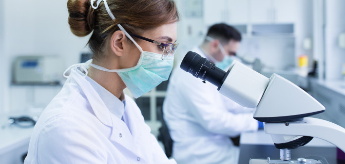 Team of experienced biologists working on microscopes in laboratory