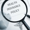 A maginfying glass looking at the words "Health Insurance Policy"