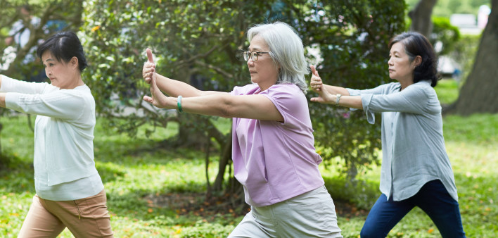 Three relaxed senior Taiwanese female friends enjoying the sunshine and tai chi at a park in Taipei.