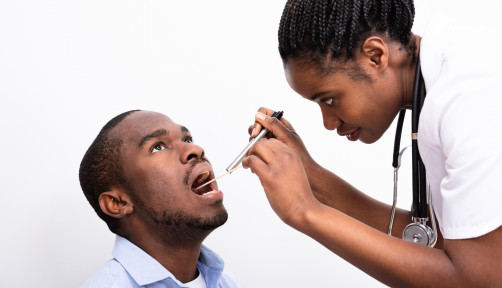 black man getting his throat checked by female nurse doctor