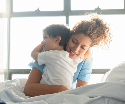 Beautiful sweet little boy hospitalized in the pediatrics ward hugging young nurse both smiling
