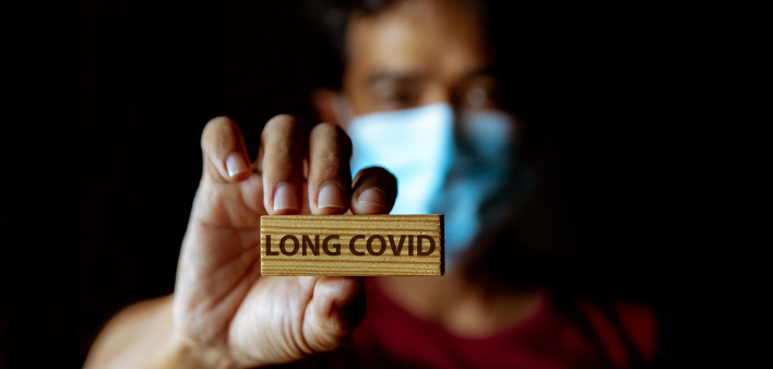 Masked Asian man show wooden sign with wording "Long Covid"