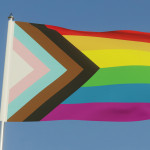 Inclusive LGBTQI+ Pride Flag Fluttering against a blue sky