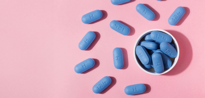 blue pills in a cup and on a pink background