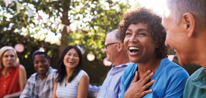 a group of adults sitting in the park laughing