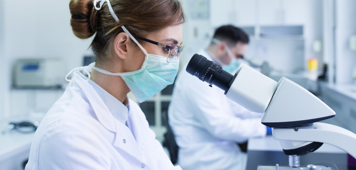 Team of experienced biologists working on microscopes in laboratory
