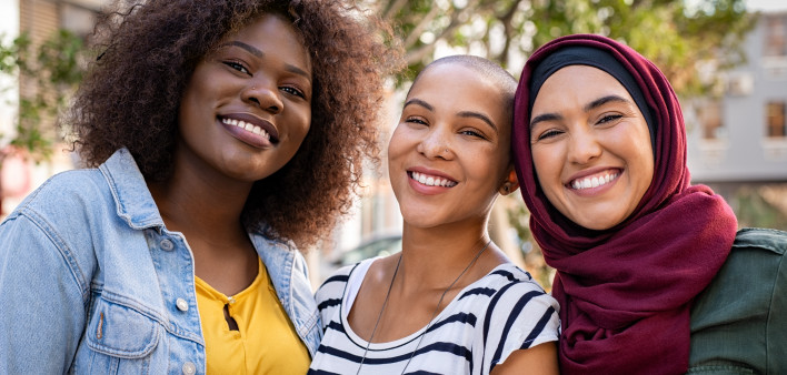 Group of three happy multiethnic friends looking at camera.