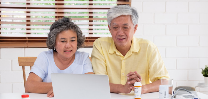 Asian couple seniors use laptop video conference with doctor about illness and prescription pill in living room at home