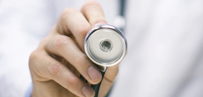 a doctors hand holding up a stethoscope