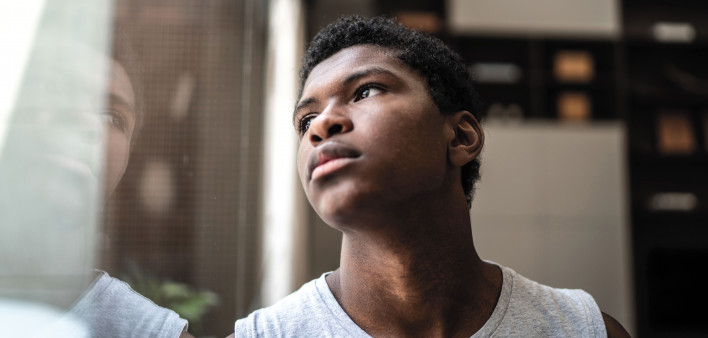 young black man looking at window