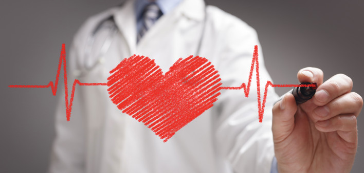 doctor in white coat drawing a red heart on glass