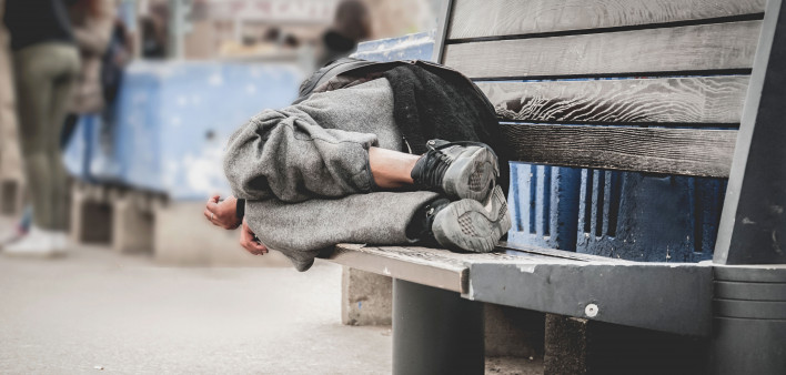 homeless man asleep on bench