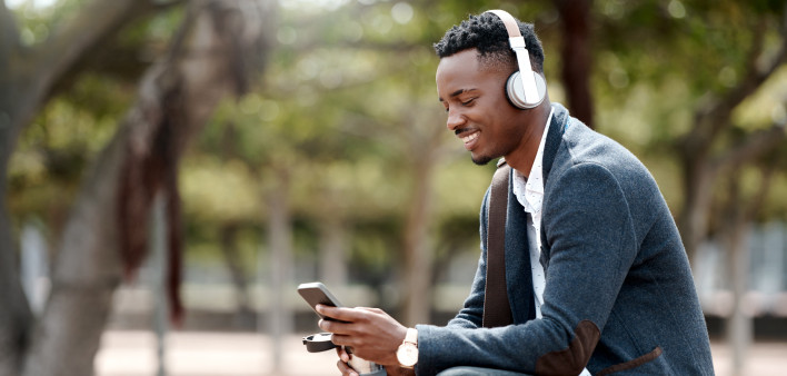 Shot of a young businessman using a smartphone and headphones in the city