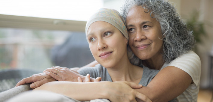 Ethnic young adult female cancer patient hugged by her mother