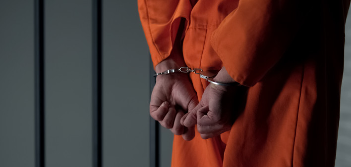 Prisoner with handcuffed arms behind back, another jail transfer, criminal