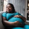 Pregnant Black woman holder her belly on couch