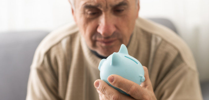 Senior caucasian man holding piggy bank with glasses depressed and worry for distress, crying angry and afraid.