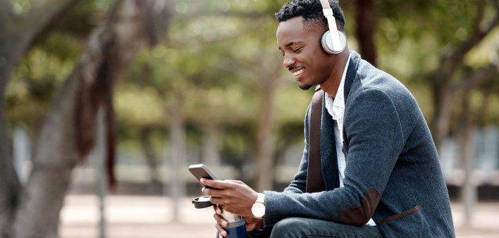Shot of a young businessman using a smartphone and headphones in the city