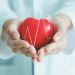Female medical doctor holding red heart shape in hand with graphic of heart beat, cardiology and insurance concept