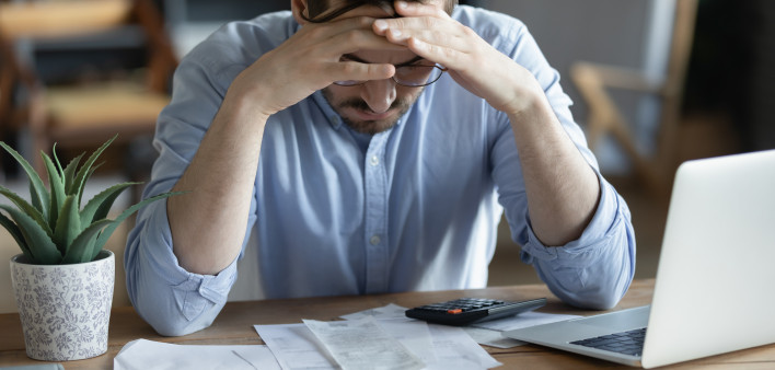 Sad depressed man checking bills, anxiety about debt or bankruptcy