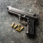 9mm pistol bullets and handgun on black table.
