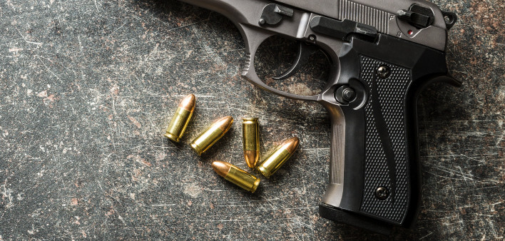 9mm pistol bullets and handgun on black table.