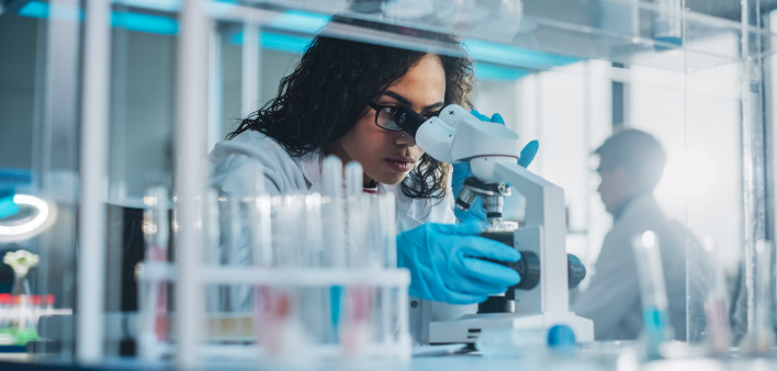 Medical Science Laboratory: Portrait of Beautiful Black Scientist Looking Under Microscope