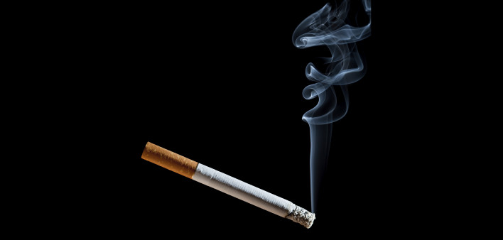 Cigarette with blue smoke on black background