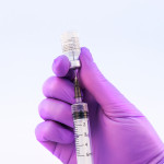 Doctor using Pfizer-BioNTech Covid-19 vaccine on a white background.