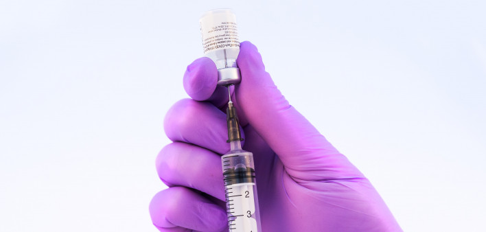 Doctor using Pfizer-BioNTech Covid-19 vaccine on a white background.