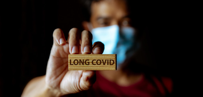 Masked Asian man show wooden sign with wording "Long Covid"