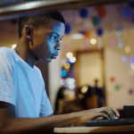 African american boy using a computer at night