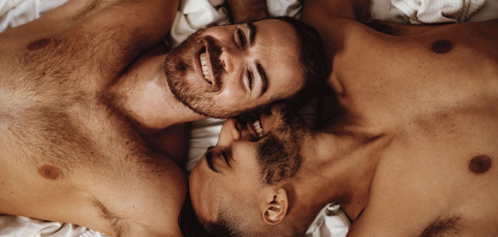 2 shirtless gay men in bed smiling