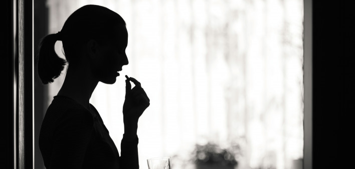 silohoutte woman taking a pill