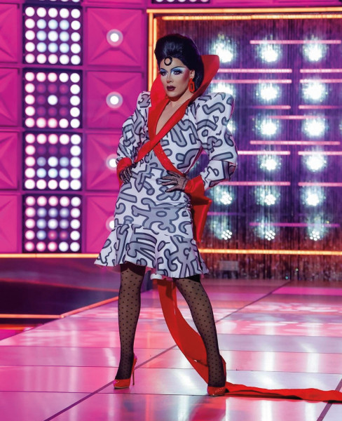 Q wears a red ribbon dress on Drag Race