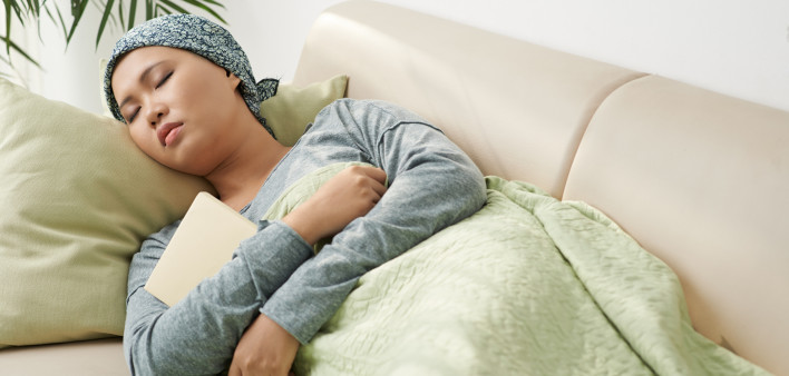Asian woman with cancer sleeping on couch