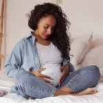 young pretty african american woman pregnant laying in bed