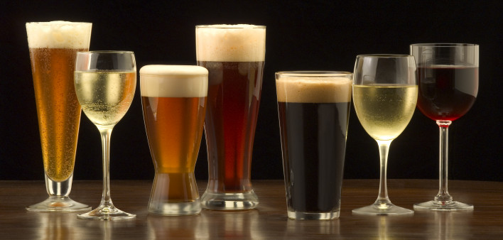 An assortment of glasses of wine and beer including a classic pilsner flute, a sparkling wine glass, an American half pint glass, a weizen or wheat beer glass, an American pint glass, a white wine glass, and a red wine glass.