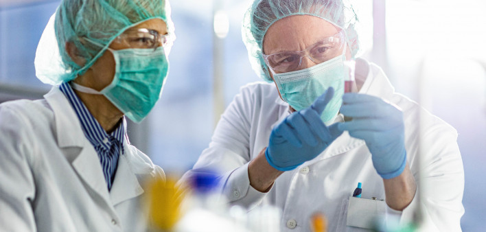 Two scientists cooperating while examining antiviral drug in a test tube at laboratory