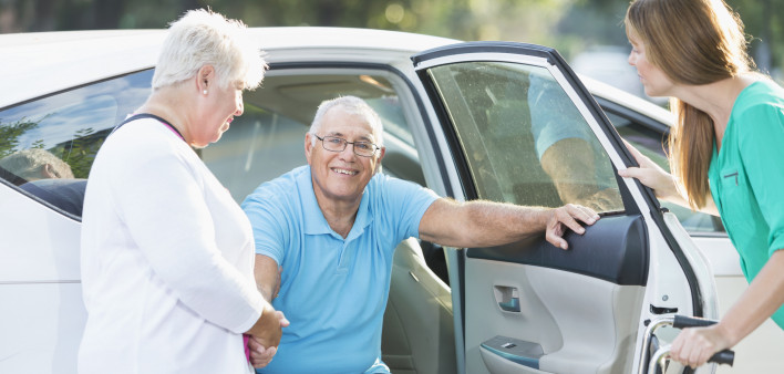 Family helping senior man from car to wheelchair s