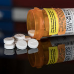 Prescription bottle for Oxycodone tablets and pills on wooden table with USA flag in background