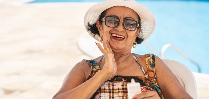 Mature woman applying suntan lotion sunscreen beach