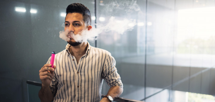 oung hispanic businessman smoking an electronic cigarette