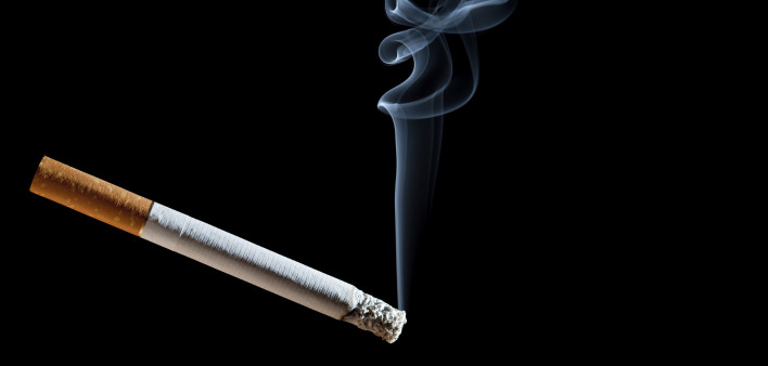 Cigarette with blue smoke on black background