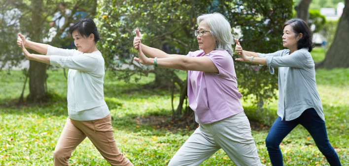 Three relaxed senior Taiwanese female friends enjoying the sunshine and tai chi at a park in Taipei.